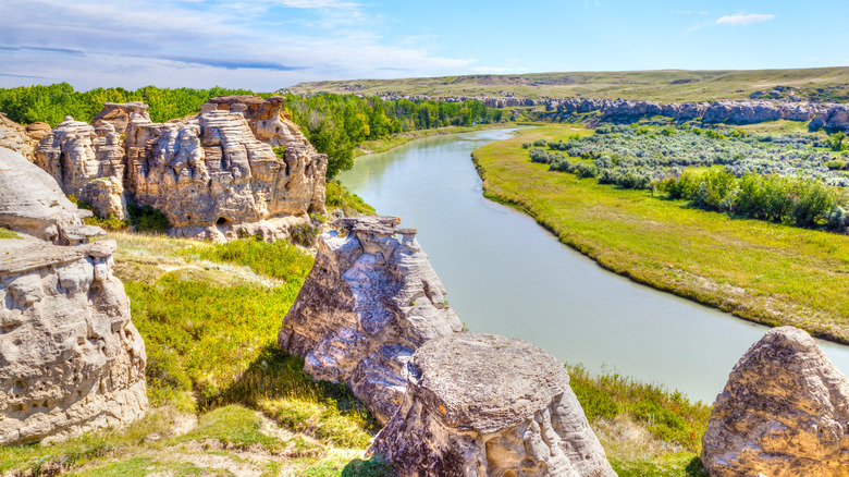 View of river, trees, and towering rock formations at Writing On Stone Provincial Park.