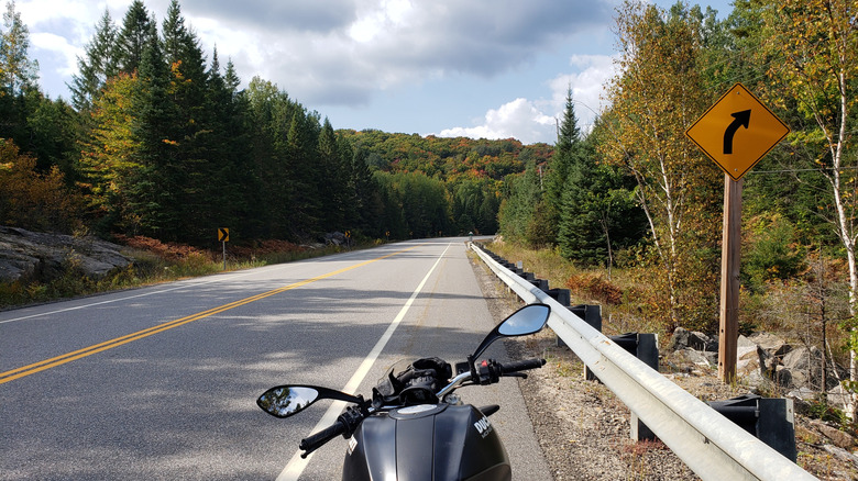 A scenic curvy road with a black Ducati motorcycle going through Algonquin Park coming from Barry's Bay, Ontario