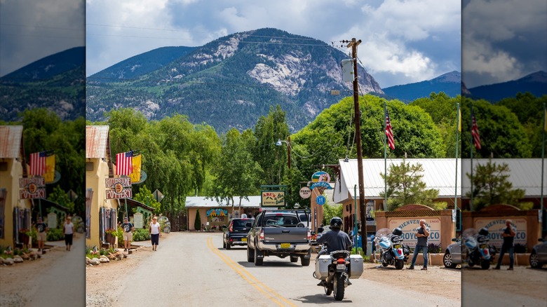 People driving through downtown Arroyo Seco with the mountains in the background