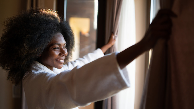Woman opening hotel room drapes