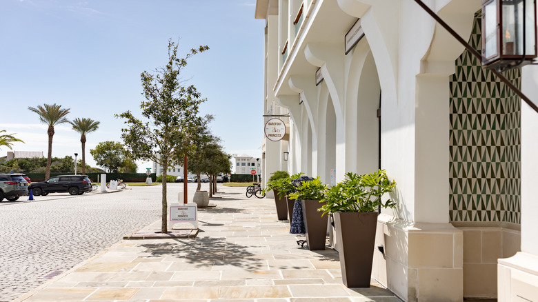 A street in ﻿﻿Florida's Alys Beach with white walls, a bicycle, and trees on the sidewalk