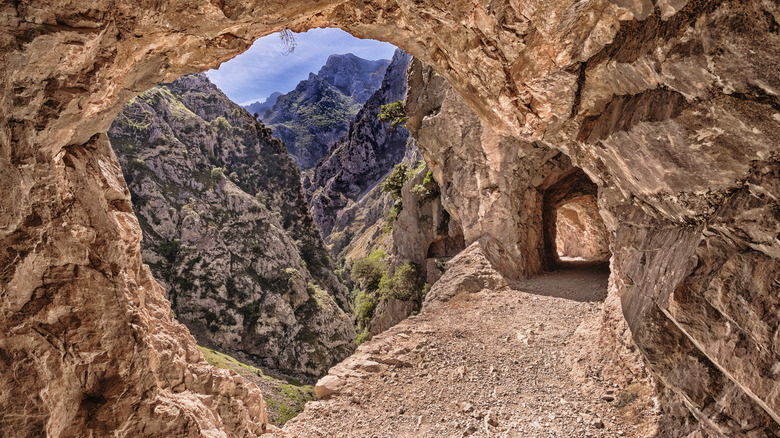 The Ruta del Cares trail winds through a tunnel on the edge of a gorge
