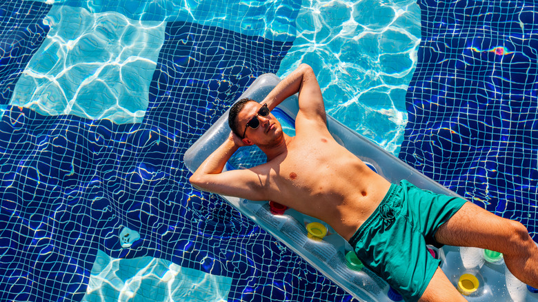Man laying on a floating mattress in a pool