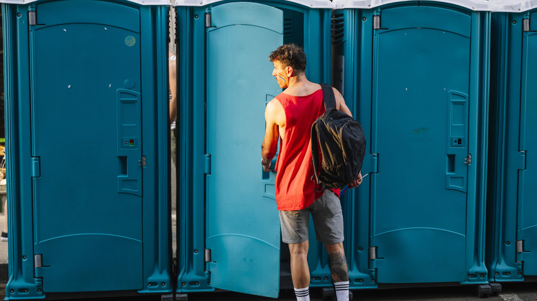 A man about to go into a portable toilet