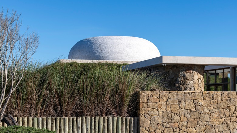 Ta Khut Skyspace, a white dome, behind grass and stone walls in Jose Ignacio