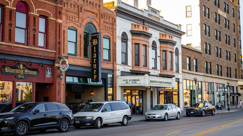 Street view of Bismarck's historic brick storefronts with cars parked outside.