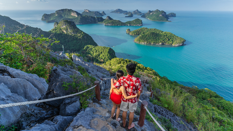 Couple stands on mountain overlooking Hawaiian islands
