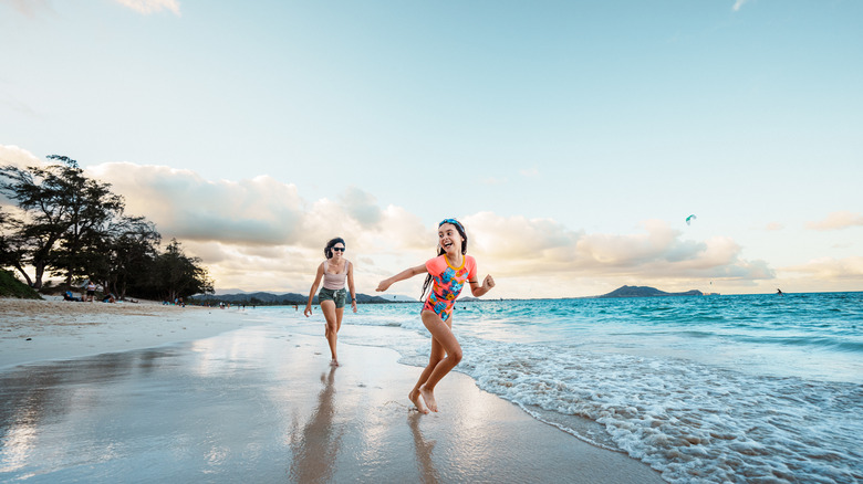 Mother and daughter run on Hawaiian beach