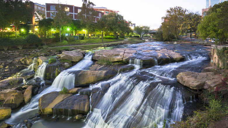 A waterfall in Greenville, South Carolina surrounded by trees and buildings