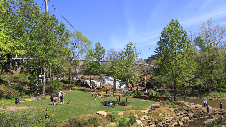 People in Falls Park by the Reedy River with a bridge and waterfall