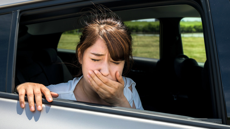 Woman looking carsick in back seat of car.