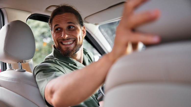 A happy parent turning to look in the backseat of the car.