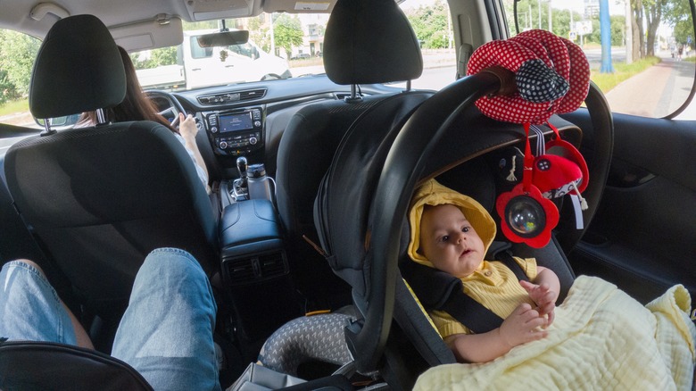 Baby in the backseat in a rear-facing car seat.