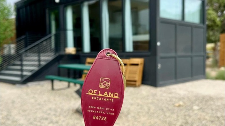 Ofland retro hotel key held up in front of deluxe cabin