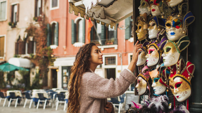 A traveler in Venice, Italy, shops for Carnival masks