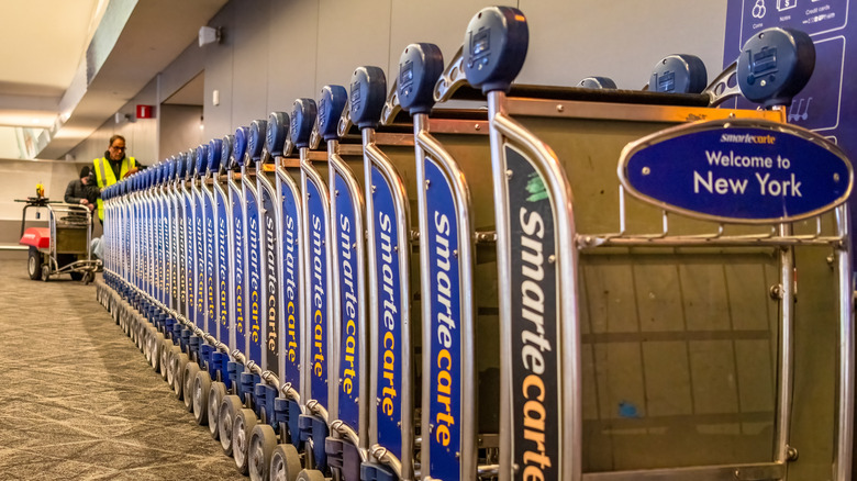 Long stack of airport luggage carts with "smart carte" brand on side