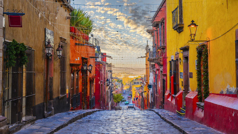 Colorful houses lining a cobbled street in Mexico during sunset