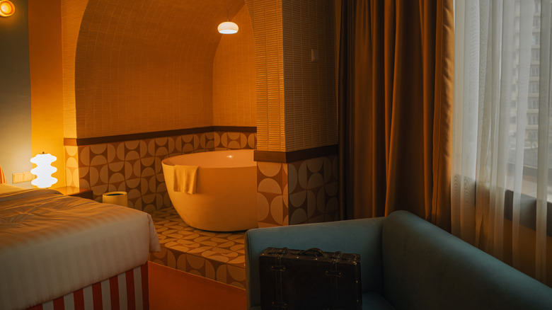 Warmly lit hotel bathroom with a bathtub in an alcove