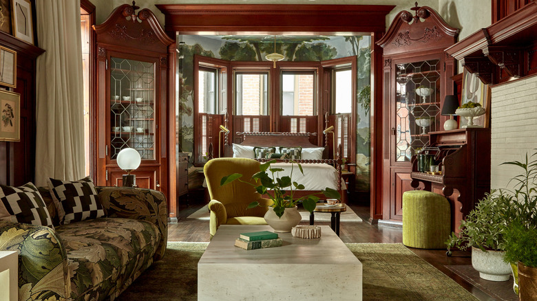 Living room suite with adjoining bedroom with green furnishings and wooden cupboards