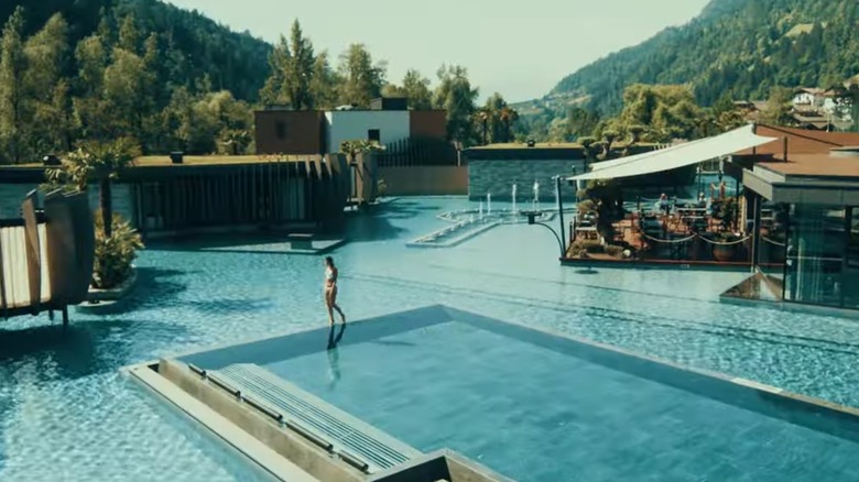 Woman walking along the edge of an infinity pool at Quellenhof See Lodge in Merano, Italy