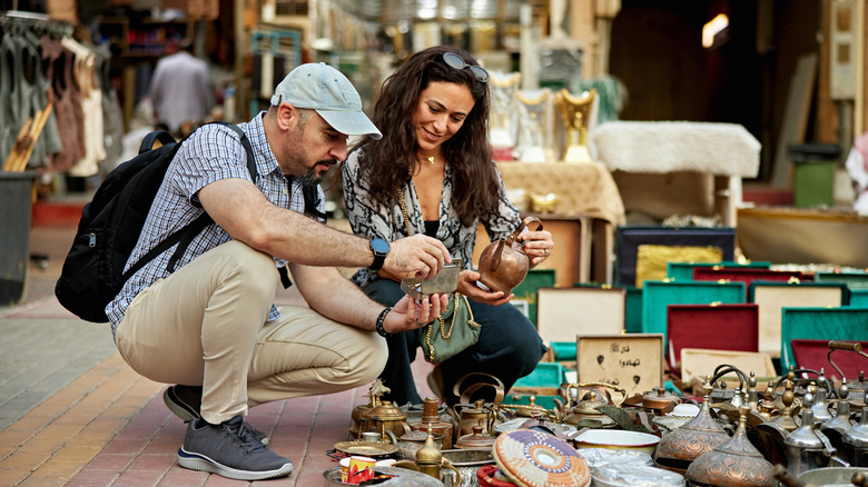 a young couple looks through local street markets for products to buy
