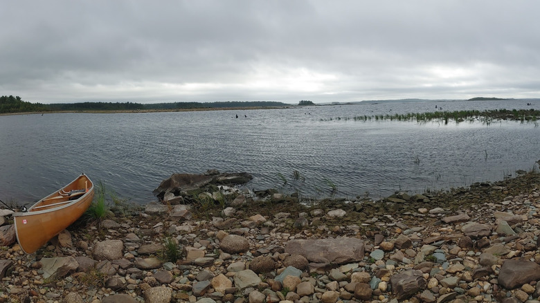 A view of  of a canoe on Lake Rossignol's rocky shore under a grey sky in Queens County, Nova Scotia, Canada