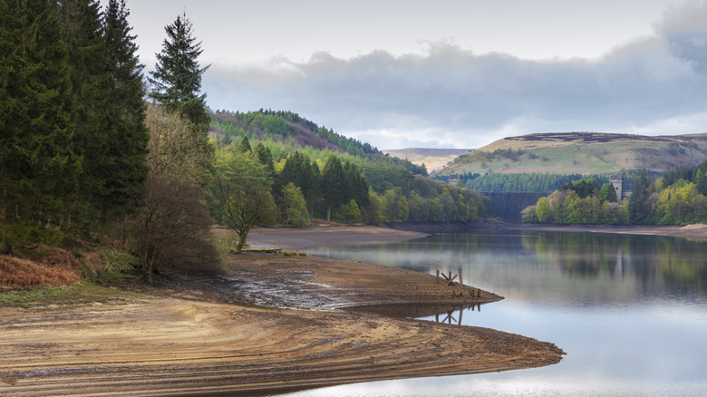 Sandy dirt shoreline along Derwent Reservoir under cloudy skies