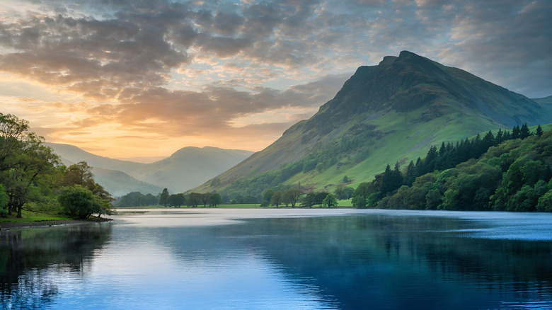 Emerald green hills and tree groves loom over the calm surface of England's Rutland Reservoir