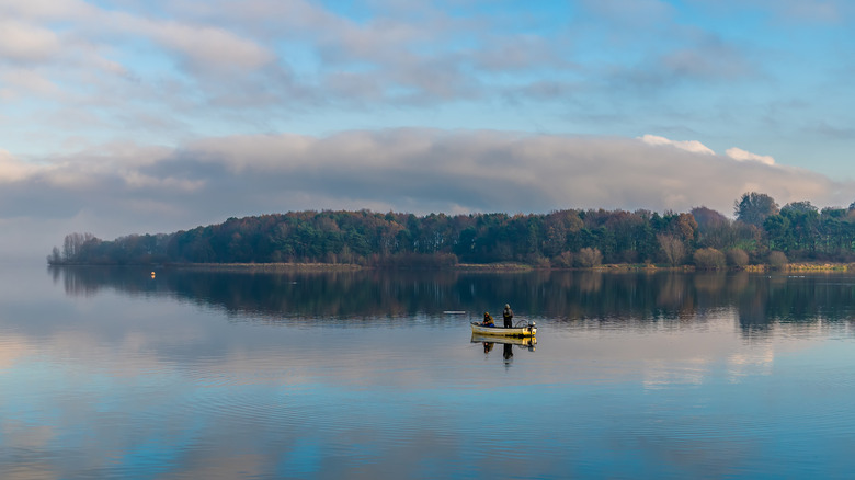 Fishermen float on the calm, reflective surface of Pitsford Water