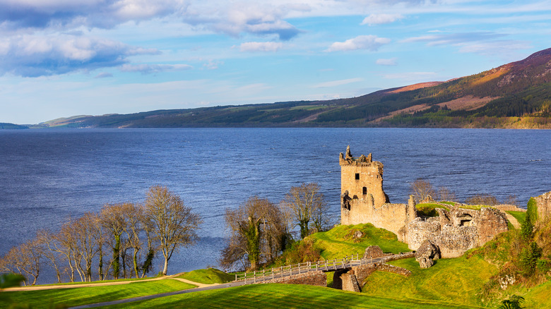 Sunlight touches the ruins of Urquhart Castle on the side of Loch Ness