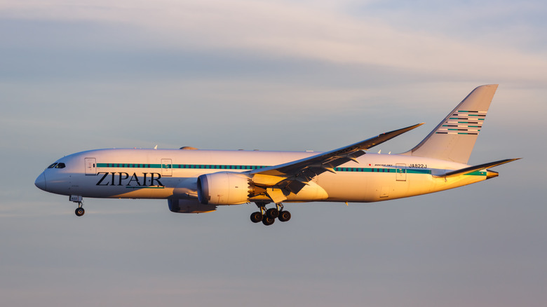 A flying airplane with the name ZIPAIR on it