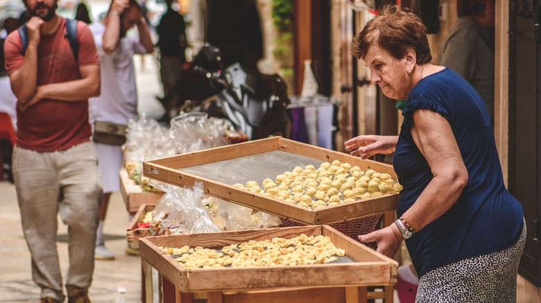 A woman making and selling fresh orecchiette in Bari, Italy