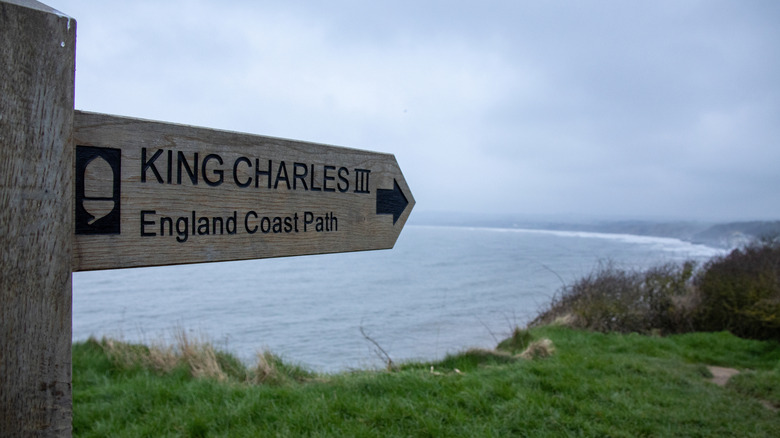 A wooden signpost for the King Charles III England Coastal Path near Filey Brigg on the Yorkshire Coast in England