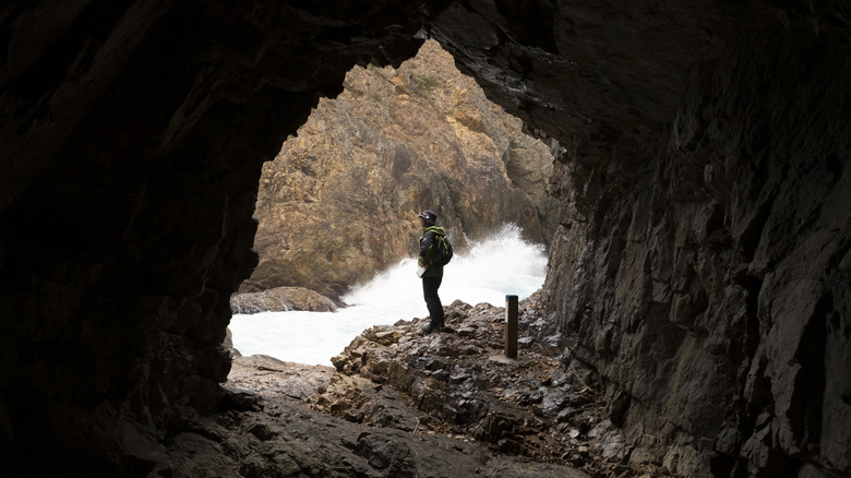 A man standing at the mouth of a cave in Japan's Michinoku Coastal Trail