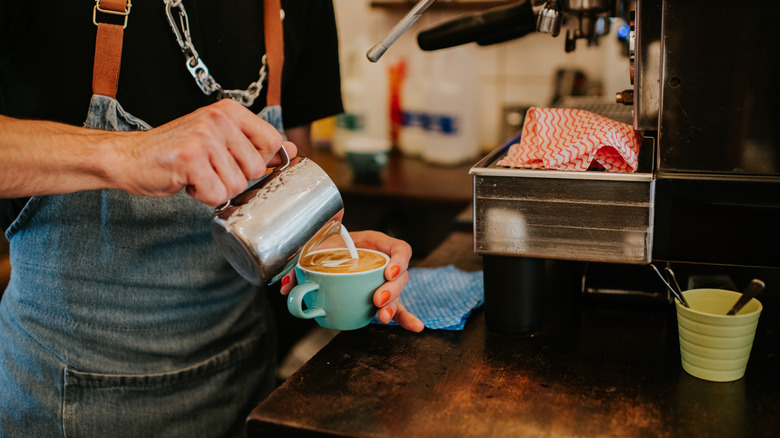 Someone pouring a latte