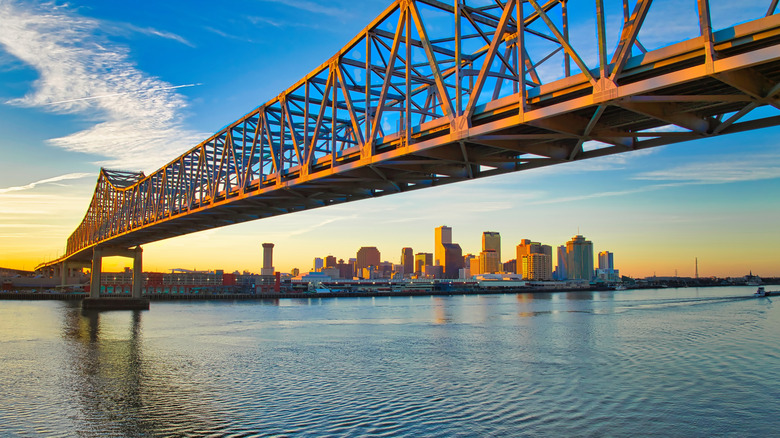Iron bridge spanning over the Mississippi River with New Orleans skyline in background