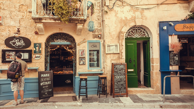 Tourist looking at menu outside stone restaurant