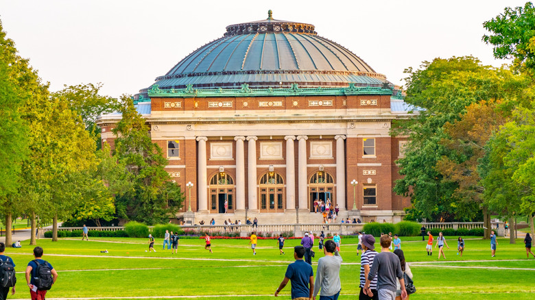 Students walk outdoors on lawn of University of Illinois college campus quad in Urbana-Champaign, Illinois