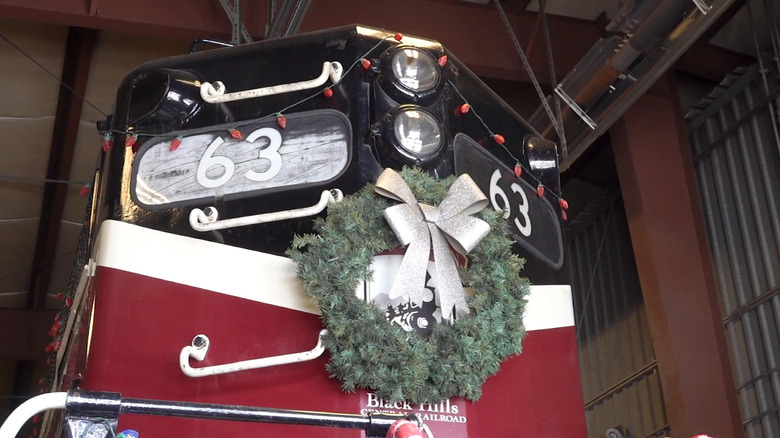 The 1880 train in a snowy bend with holiday lights as decorations