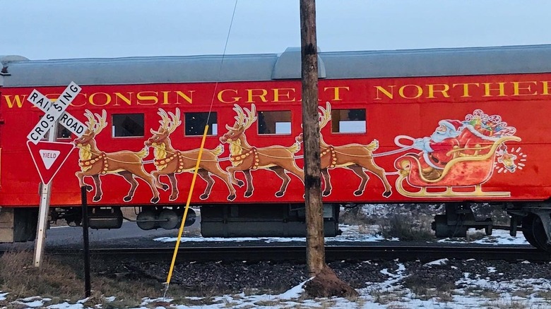 A red train car with Christmas decor and snow
