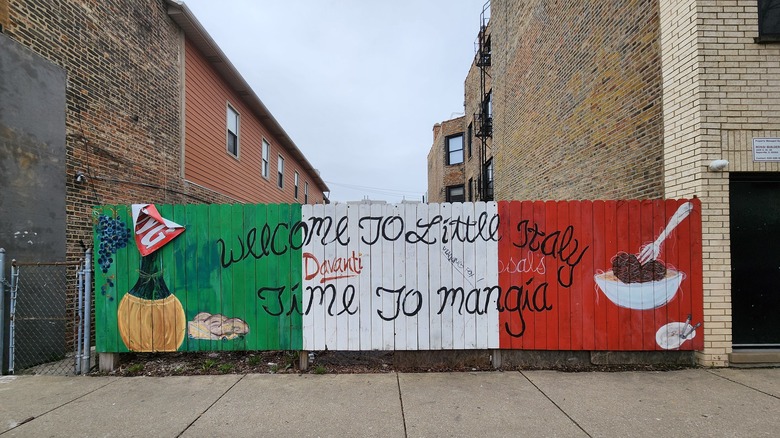 A sign written over a picket fence reads: "Welcome to Little Italy, Time to Mangia" in Chicago, Illinois