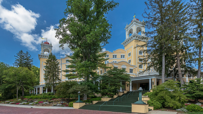 Elegant gold and white turreted hotel surrounded by forest