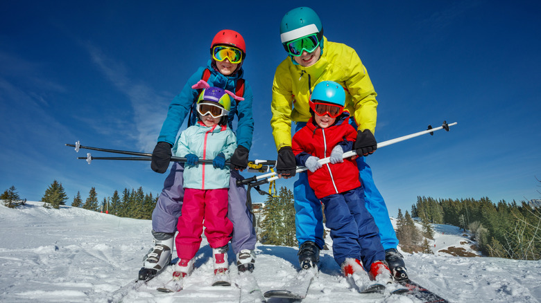 Parents and two young children with their skis at the top of a hill