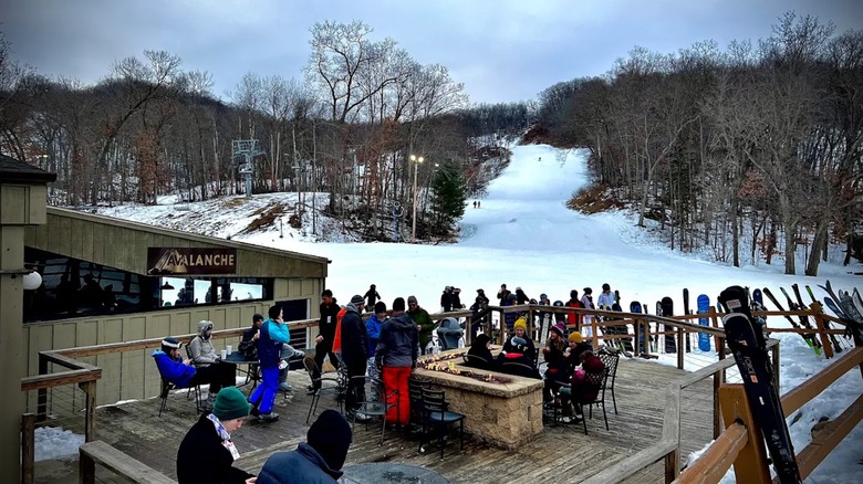 Skiers and snowboarders around a fire pit at Devil's Head Resort