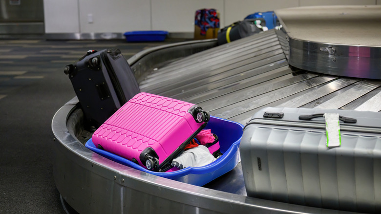 Broken suitcase in a plastic bin at baggage claim