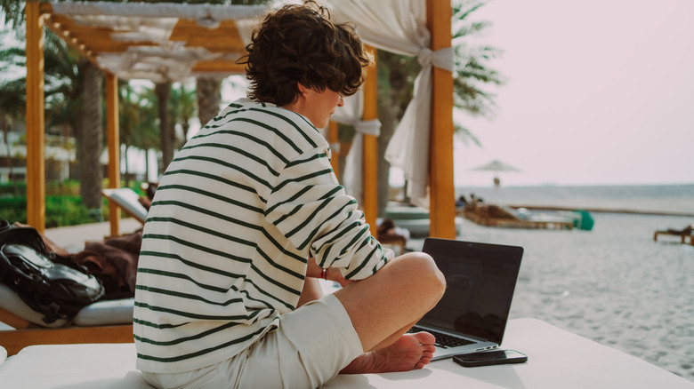 Woman working with a laptop by the beach