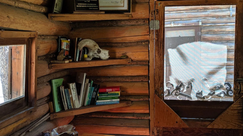A corner shelf with a bunch of books, an animal skull, and memorial certificates inside of Muir Trail Ranch, California