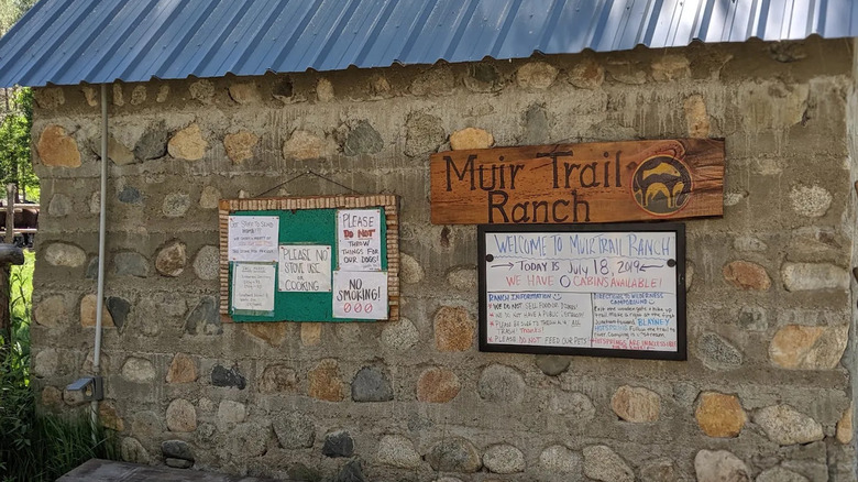 An exterior stone wall with signage at Muir Trail Ranch in California