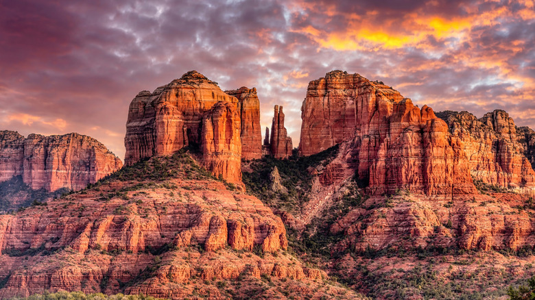Dramatic orange, red, and purple sunset over red cliffs at Cathedral Rock, Arizona