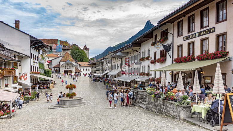 A busy town square in a Swiss old town with a castle peeking faraway